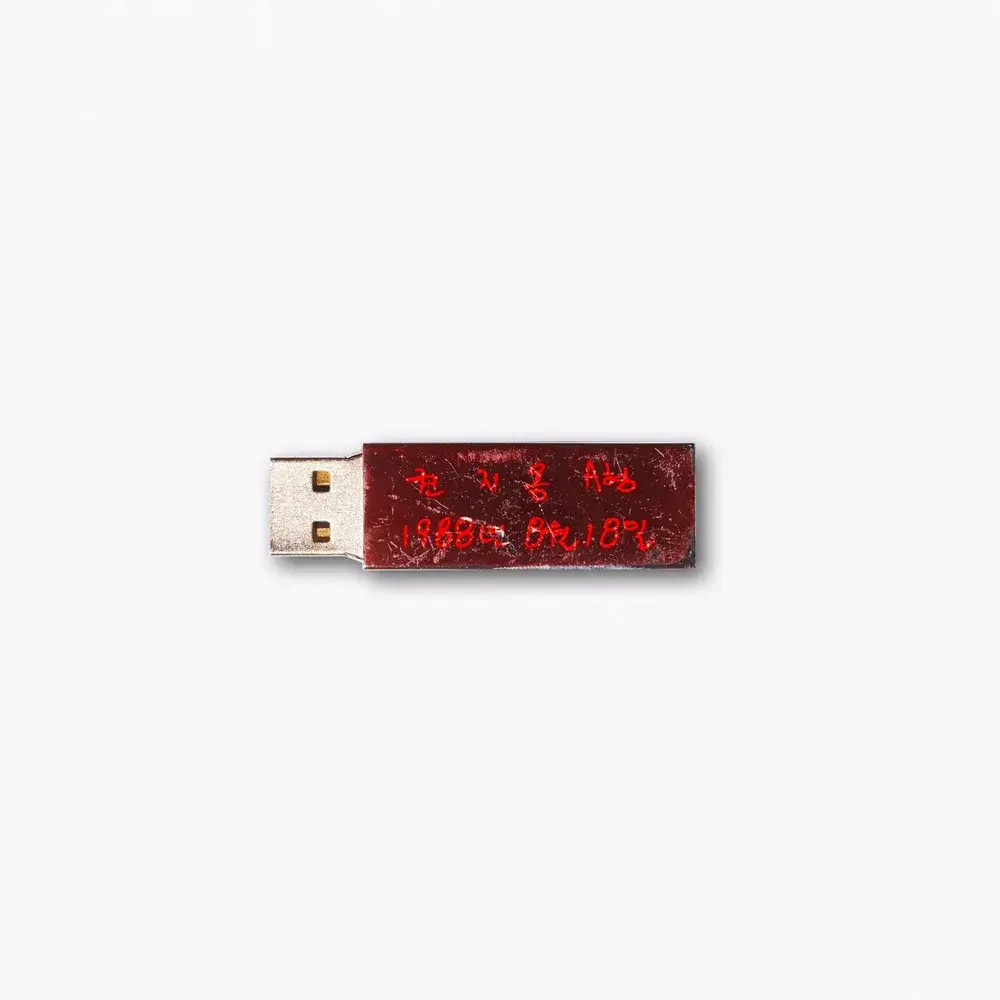 지드래곤 미니앨범 《권지용》의 USB 앨범 이미지. 밝은 회백색 배경 한가운데에 짙은 붉은색 USB 메모리 하나가 놓여 있고, 표면에는 손으로 급하게 갈겨쓴 듯한 붉은 필기체로 이름과 생년월일이 새겨져 있다. 은색 단자가 그대로 드러난 낡고 긁힌 몸체는, 화려한 무대 위의 이름이 아닌 한 사람의 신상 정보만을 남겨둔 앨범의 콘셉트를 그대로 드러낸다. 지드래곤 무제 가사